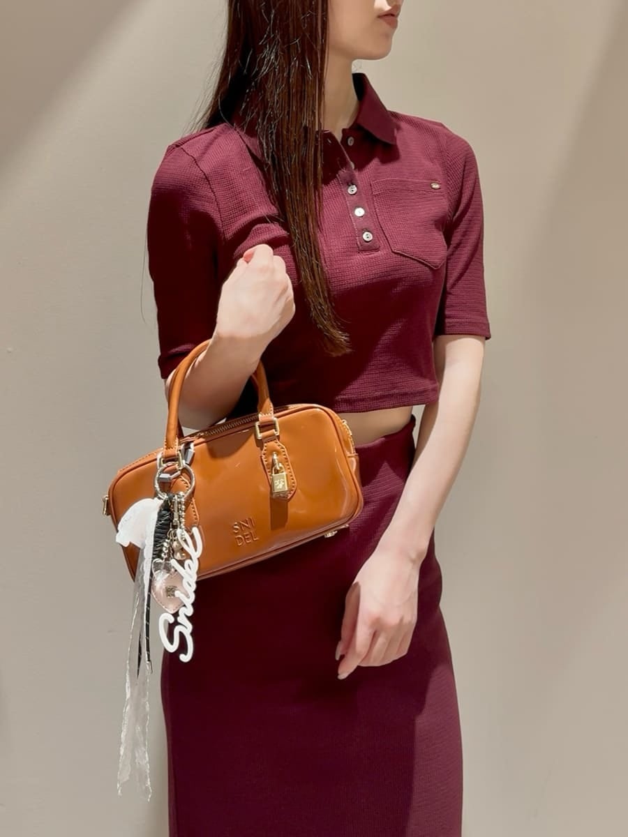 ブラウン系のワンピース、ブラウン系のボストンバッグ、ホワイト系のチャームを着用したレディースの秋コーディネートの5枚目の写真