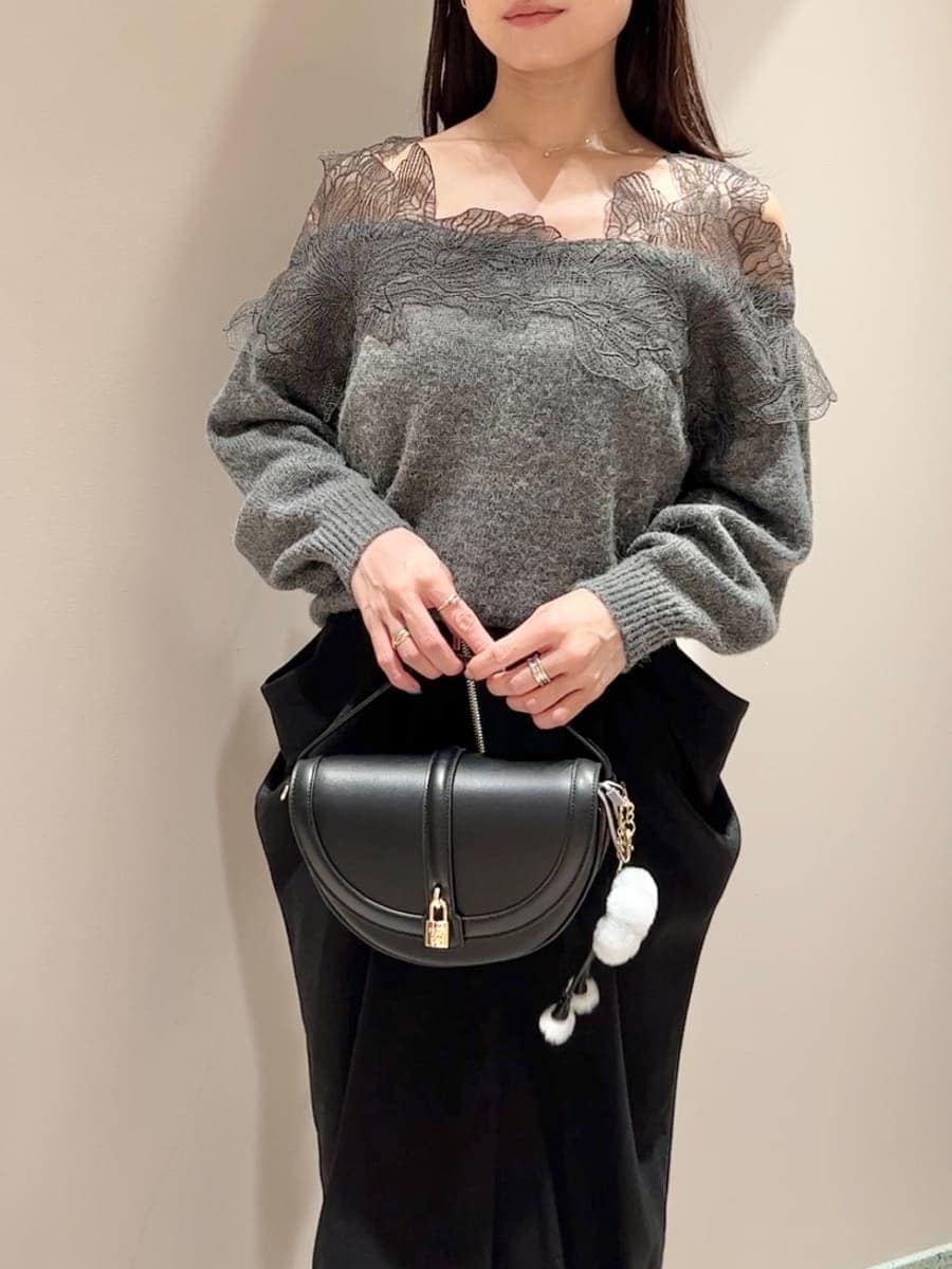 グレー系のニット/セーター、ブラック系のスカート、ブラック系のハンドバッグを着用したレディースの秋コーディネートの4枚目の写真