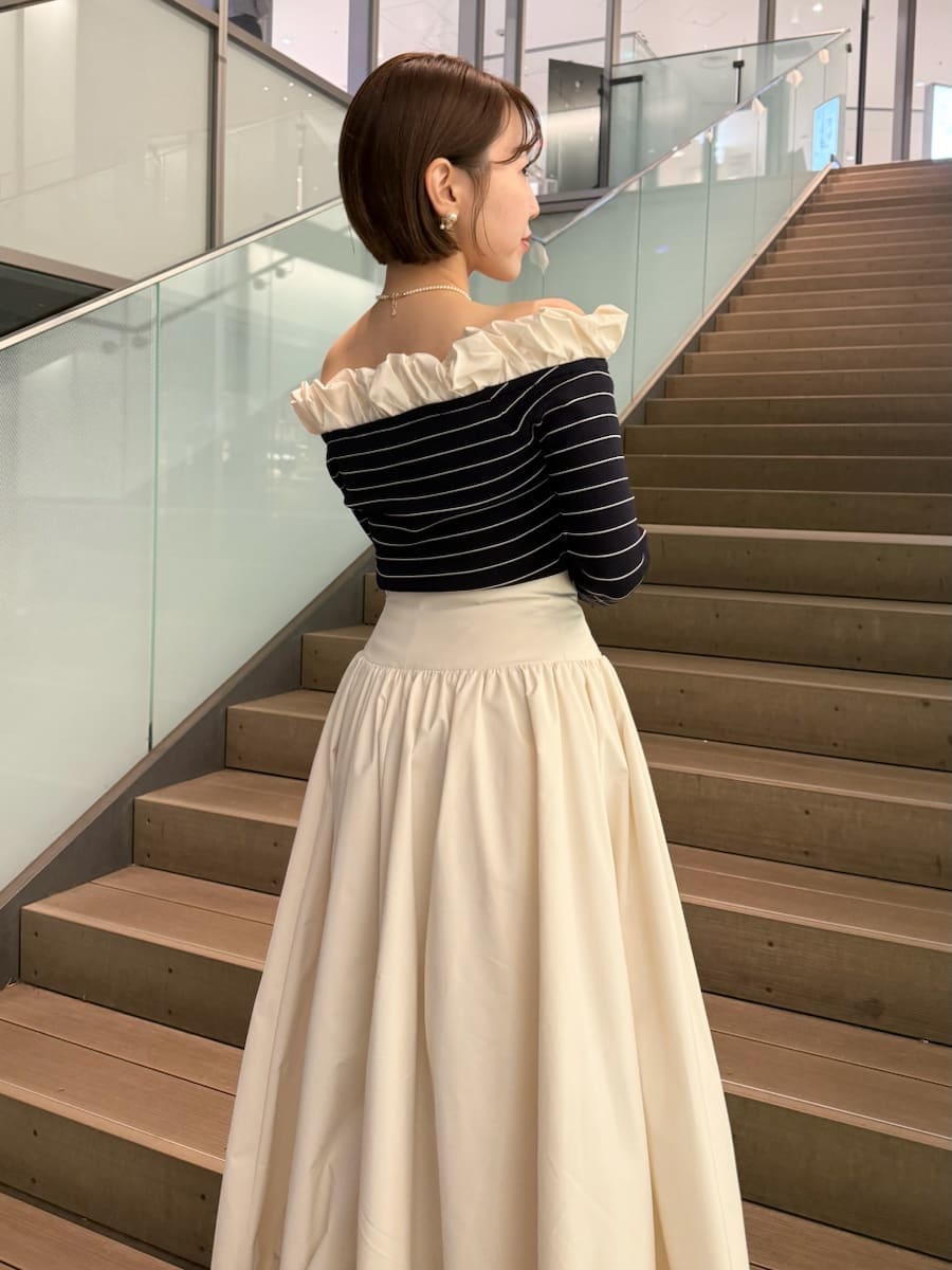 ベージュ系のトレンチコート、ホワイト系のスカート、その他のニット/セーターを着用したレディースの冬コーディネートの6枚目の写真