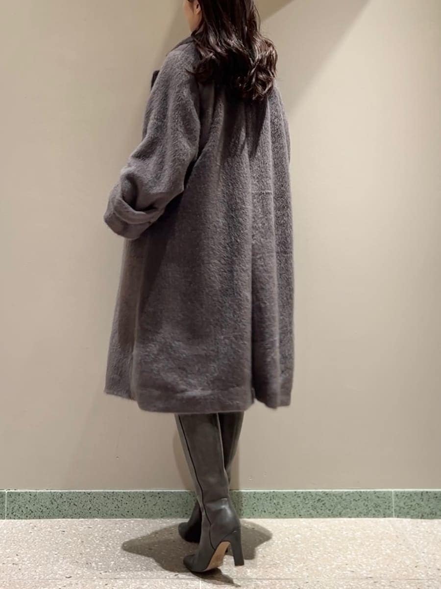 グレー系のブーツ、グレー系のチェスターコート、ブラック系のドレスを着用したレディースの冬コーディネートの3枚目の写真