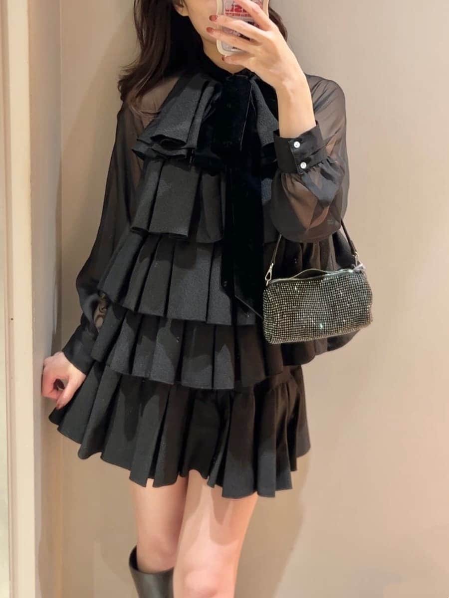 グレー系のブーツ、グレー系のチェスターコート、ブラック系のドレスを着用したレディースの冬コーディネートの8枚目の写真