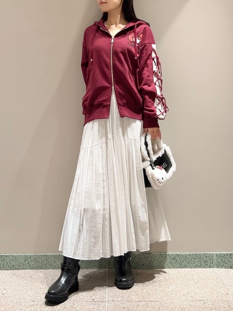 レッド系のパーカー、ホワイト系のスカート、ブラック系のハンドバッグを着用したレディースの秋コーディネートの2枚目の写真