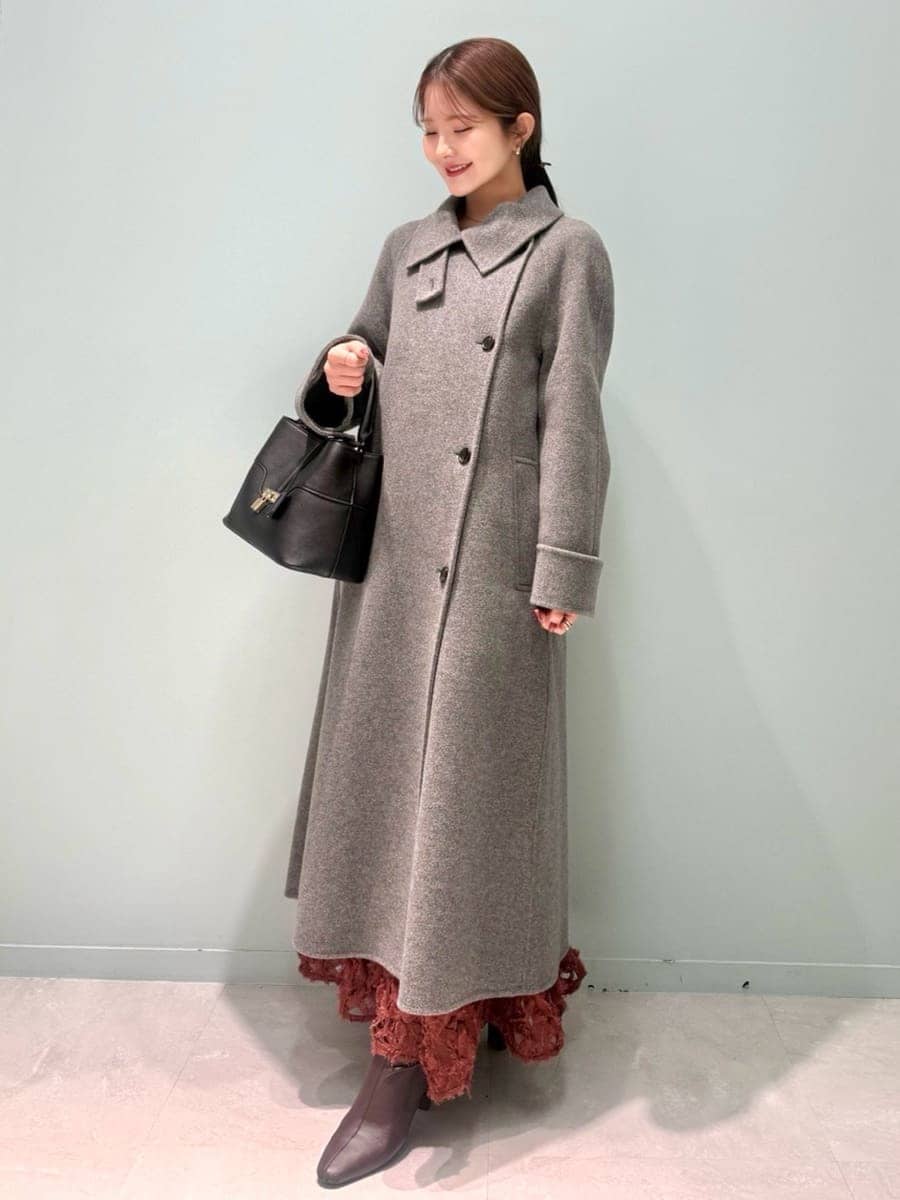 レッド系のブーツ、グレー系のチェスターコート、レッド系のスカートを着用したレディースの冬コーディネートの5枚目の写真