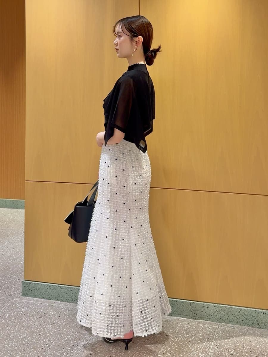 ブラック系のパンプス、ブラック系のハンドバッグ、その他のイヤリングを着用したレディースの春コーディネートの2枚目の写真