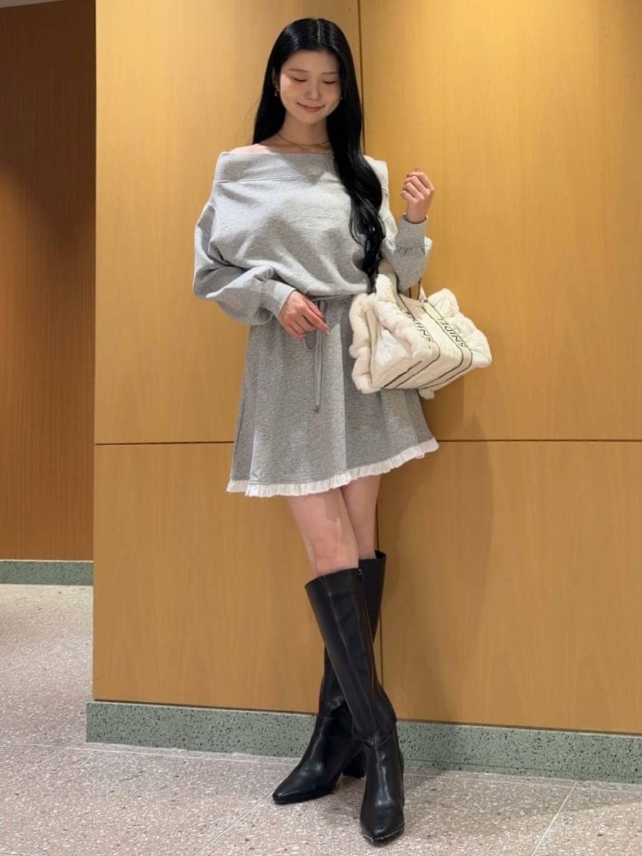 グレー系のワンピース、ブラック系のブーツ、ホワイト系のショルダーバッグを着用したレディースの秋コーディネートの2枚目の写真