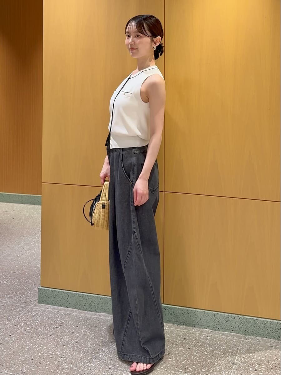 ブラック系のかごバッグ、ブラック系のデニムパンツ、ホワイト系のニット/セーターを着用したレディースの夏コーディネートの2枚目の写真