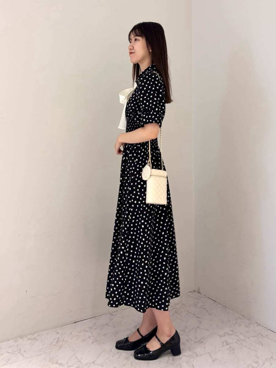 ブラック系のワンピース、ホワイト系のショルダーバッグ、ブラック系のパンプスを着用したレディースの夏コーディネートの2枚目の写真