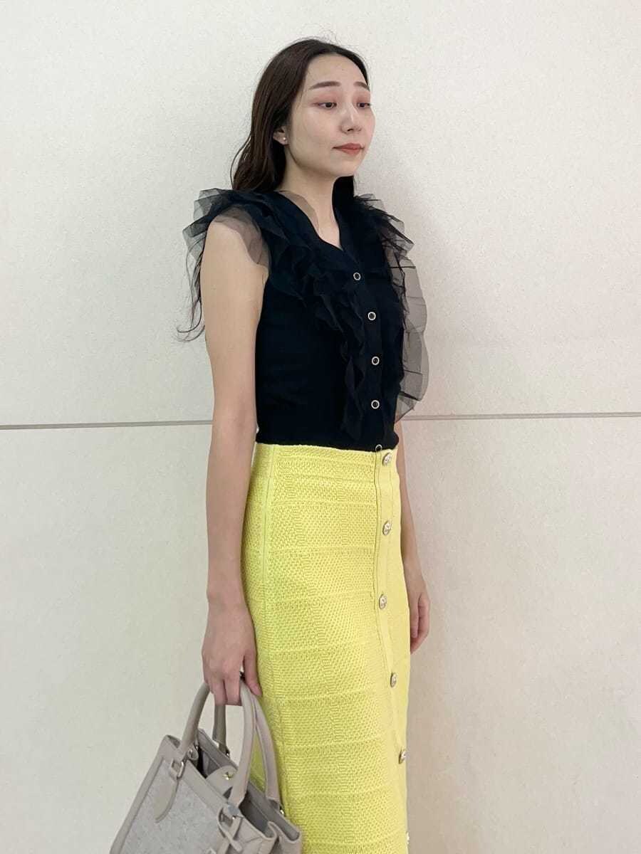 ブラック系のニット/セーター、イエロー系のスカート、ピンク系のハンドバッグを着用したレディースの夏コーディネートの6枚目の写真