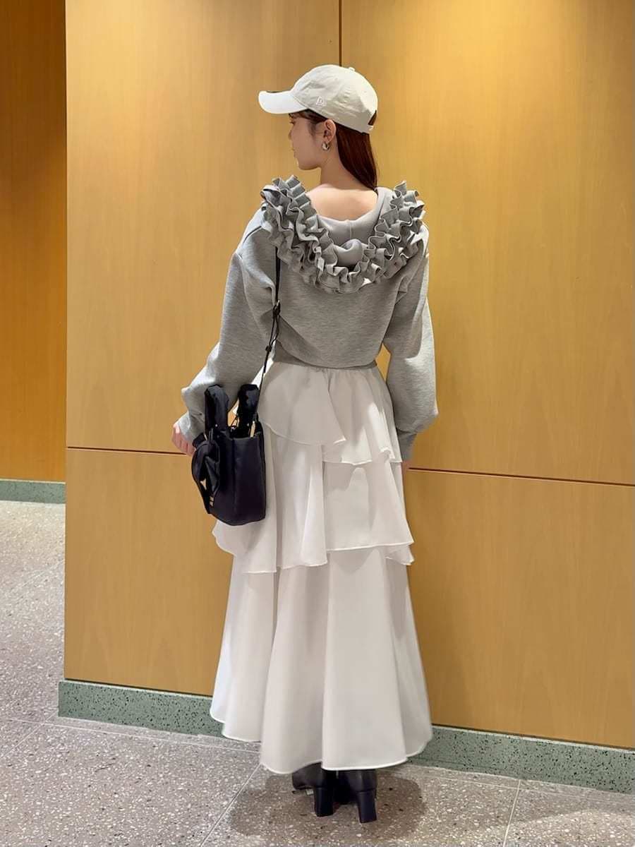 イエロー系のワンピース、グレー系のパーカー、シルバー系のピアス（両耳用）を着用したレディースの冬コーディネートの3枚目の写真