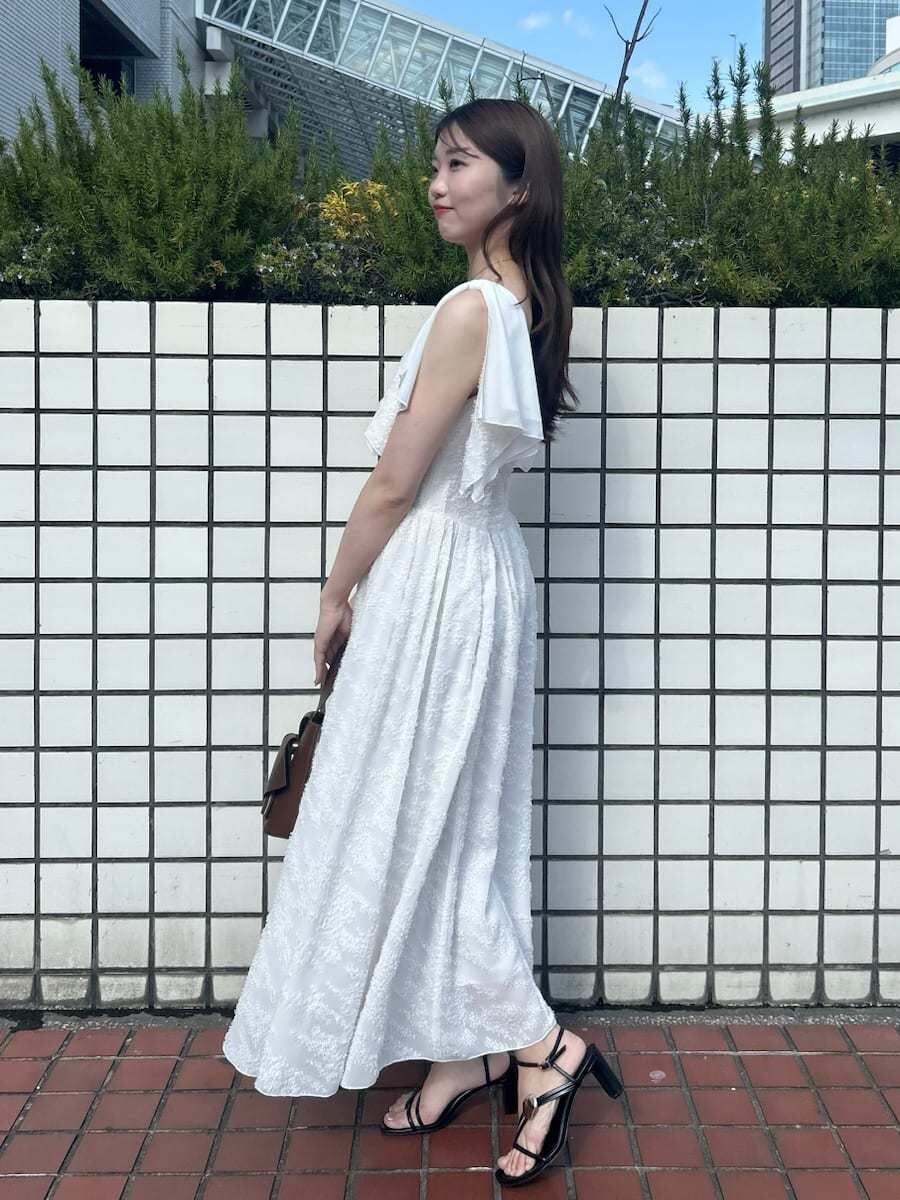ホワイト系のワンピース、ブラウン系のハンドバッグ、ピンク系の折りたたみ傘を着用したレディースの春コーディネートの5枚目の写真