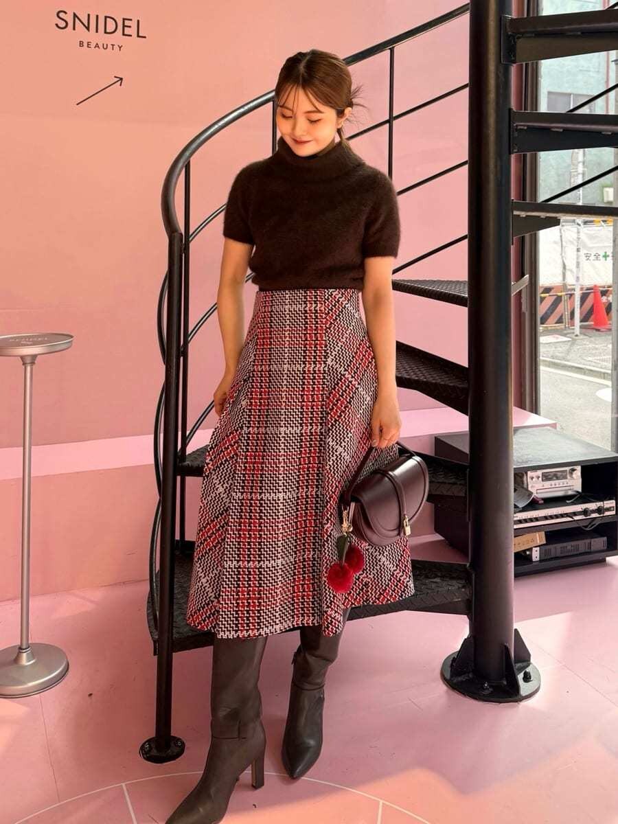 ブラウン系のニット/セーター、レッド系のスカート、ブラウン系のブーツを着用したレディースの秋コーディネートの4枚目の写真