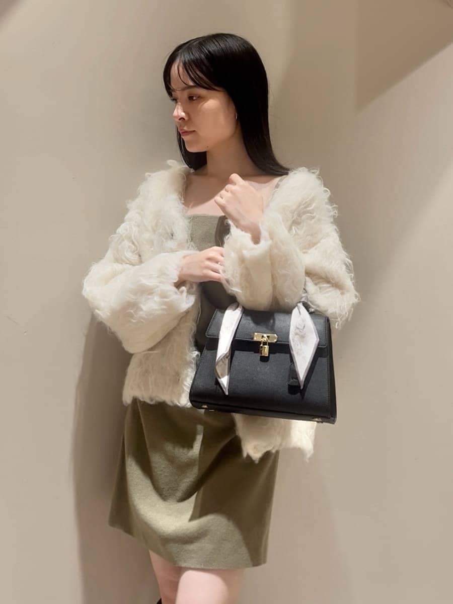 グリーン系のワンピース、ホワイト系のカーディガン/ボレロ、ブラック系のブーツを着用したレディースの秋コーディネートの4枚目の写真