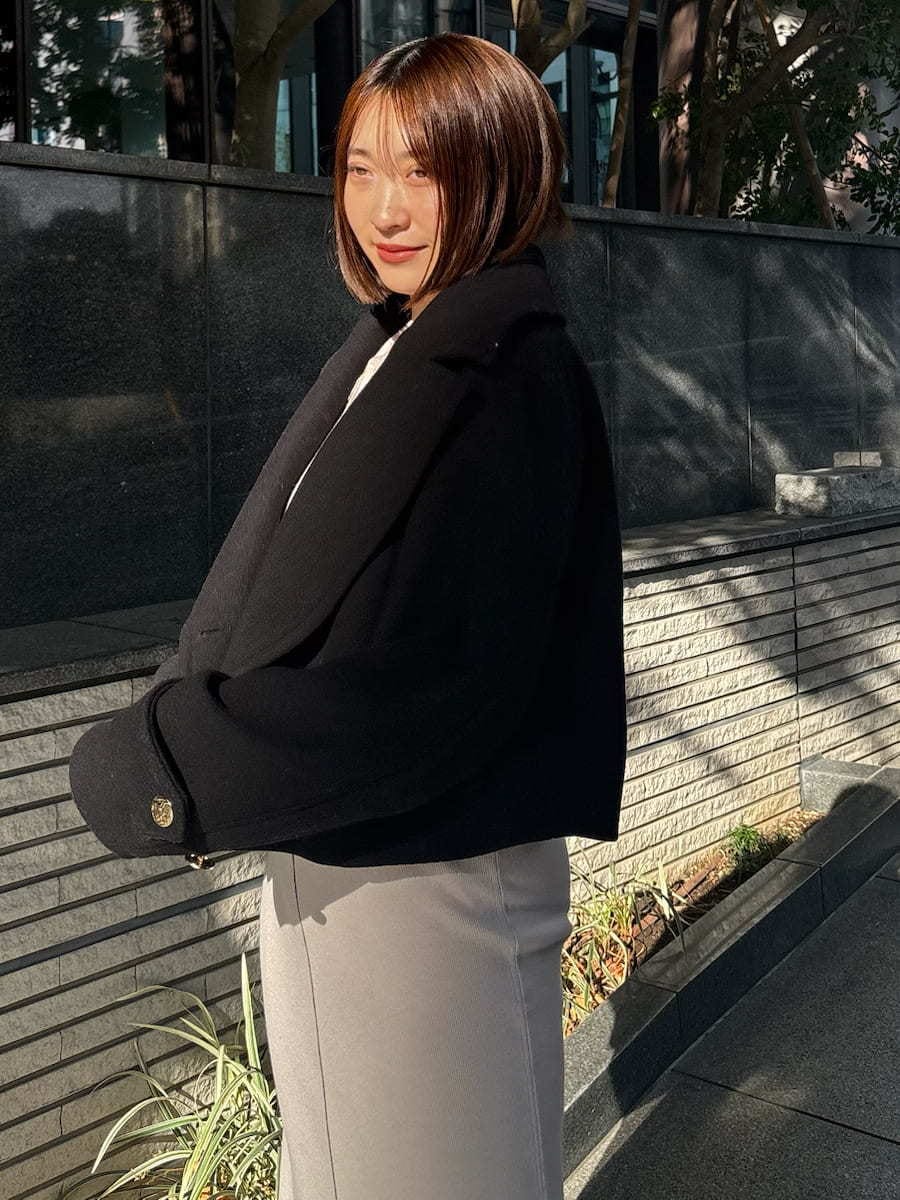 ブラック系のピーコート、ホワイト系のワンピース、ホワイト系のショルダーバッグを着用したレディースの冬コーディネートの4枚目の写真