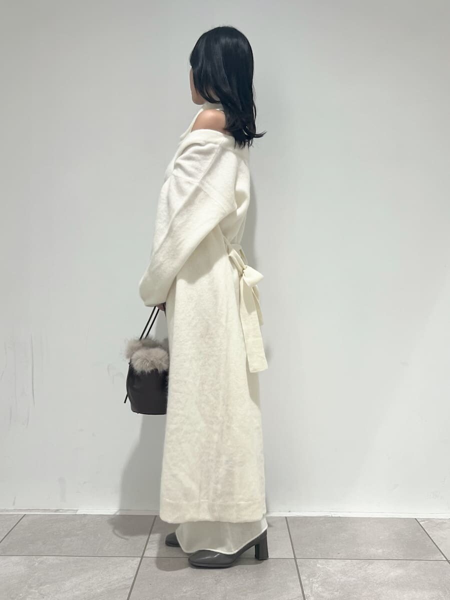 ホワイト系のチェスターコート、ホワイト系のワンピース、ブラウン系のハンドバッグを着用したレディースの冬コーディネートの2枚目の写真