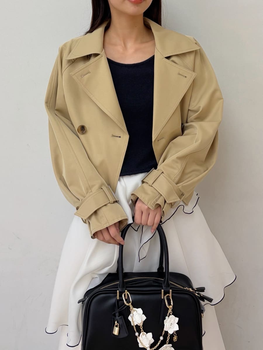 ベージュ系のトレンチコート、ブルー系のワンピース、ブラック系のパンプスを着用したレディースの冬コーディネートの5枚目の写真