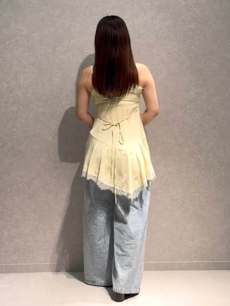 ブルー系のデニムパンツ、ブラウン系のボストンバッグ、イエロー系のキャミソールを着用したレディースの夏コーディネートの4枚目の写真