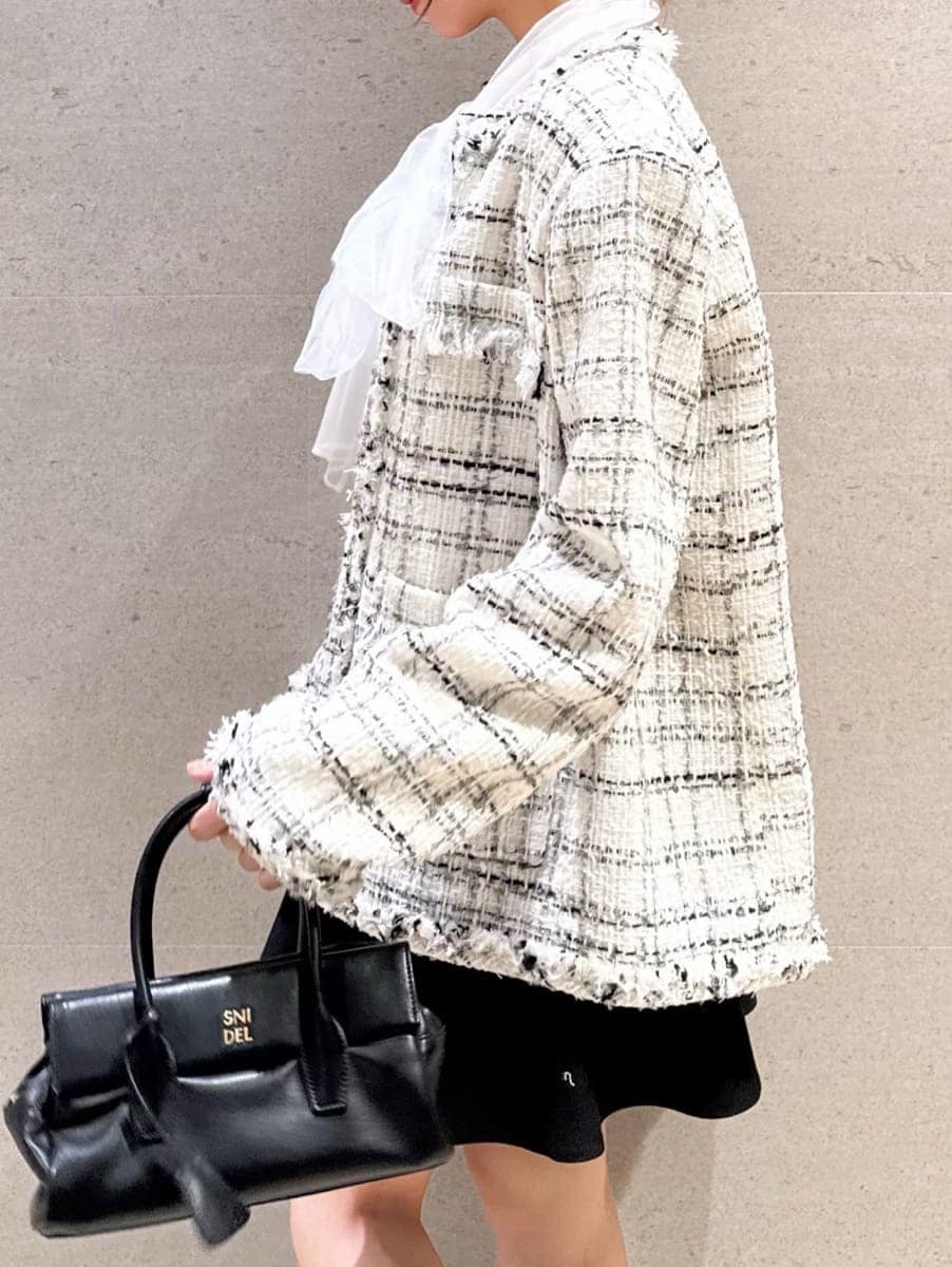 ブラック系のボストンバッグ、ホワイト系のノーカラージャケット、ブラック系のその他パンツを着用したレディースの冬コーディネートの4枚目の写真