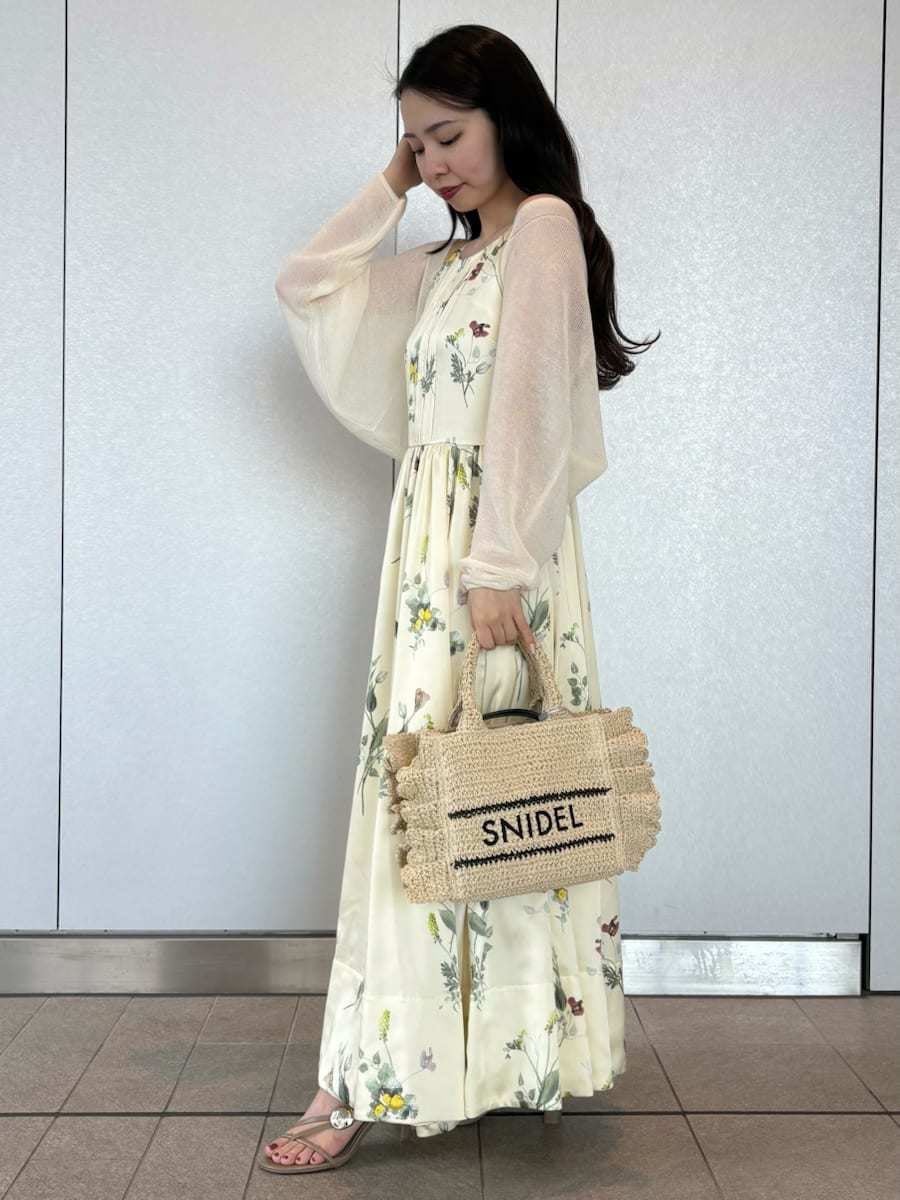 イエロー系のワンピース、ホワイト系のカーディガン/ボレロ、ベージュ系のショルダーバッグを着用したレディースの春コーディネートの2枚目の写真