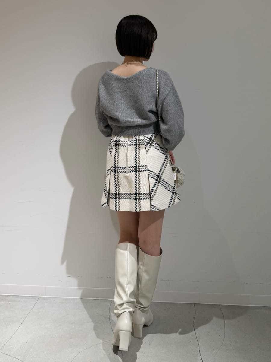 ホワイト系のスカート、グレー系のカーディガン/ボレロ、ゴールド系のキーケース/キーアクセサリーを着用したレディースの冬コーディネートの2枚目の写真