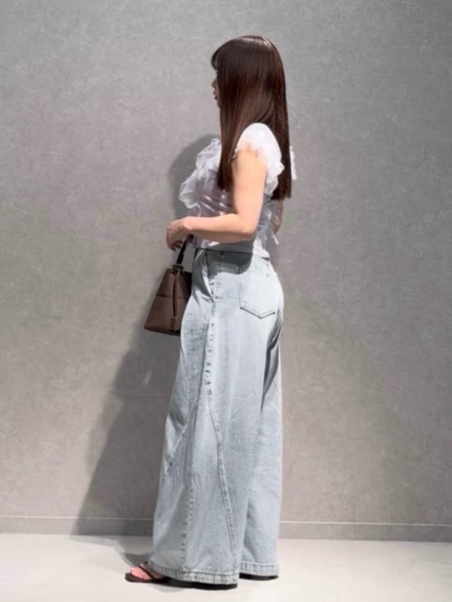 ブラウン系のハンドバッグ、ブルー系のデニムパンツ、パープル系のニット/セーターを着用したレディースの夏コーディネートの3枚目の写真
