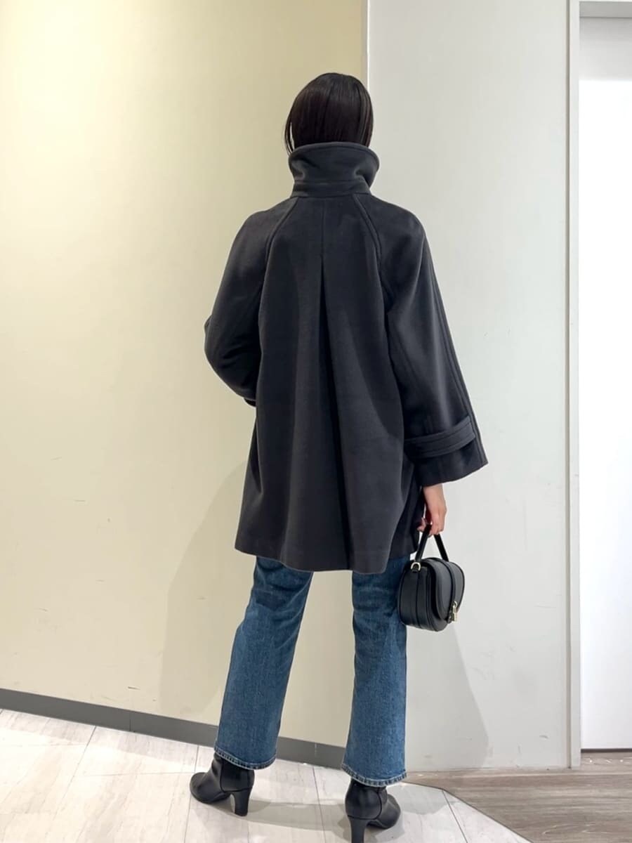 グレー系のステンカラーコート、レッド系のニット/セーター、ブルー系のデニムパンツを着用したレディースの秋コーディネートの10枚目の写真