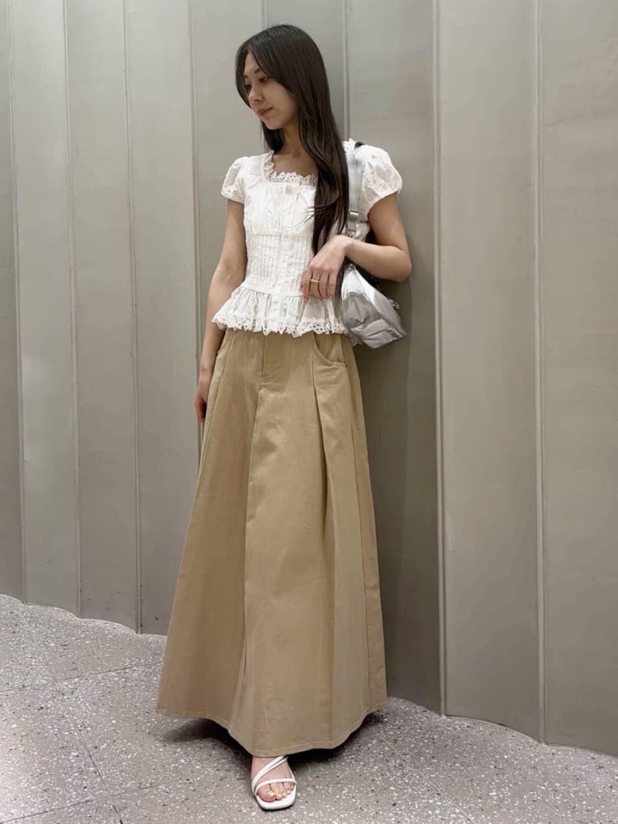 ベージュ系のスカート、ホワイト系のシャツ/ブラウス、シルバー系のショルダーバッグを着用したレディースの春コーディネートの2枚目の写真