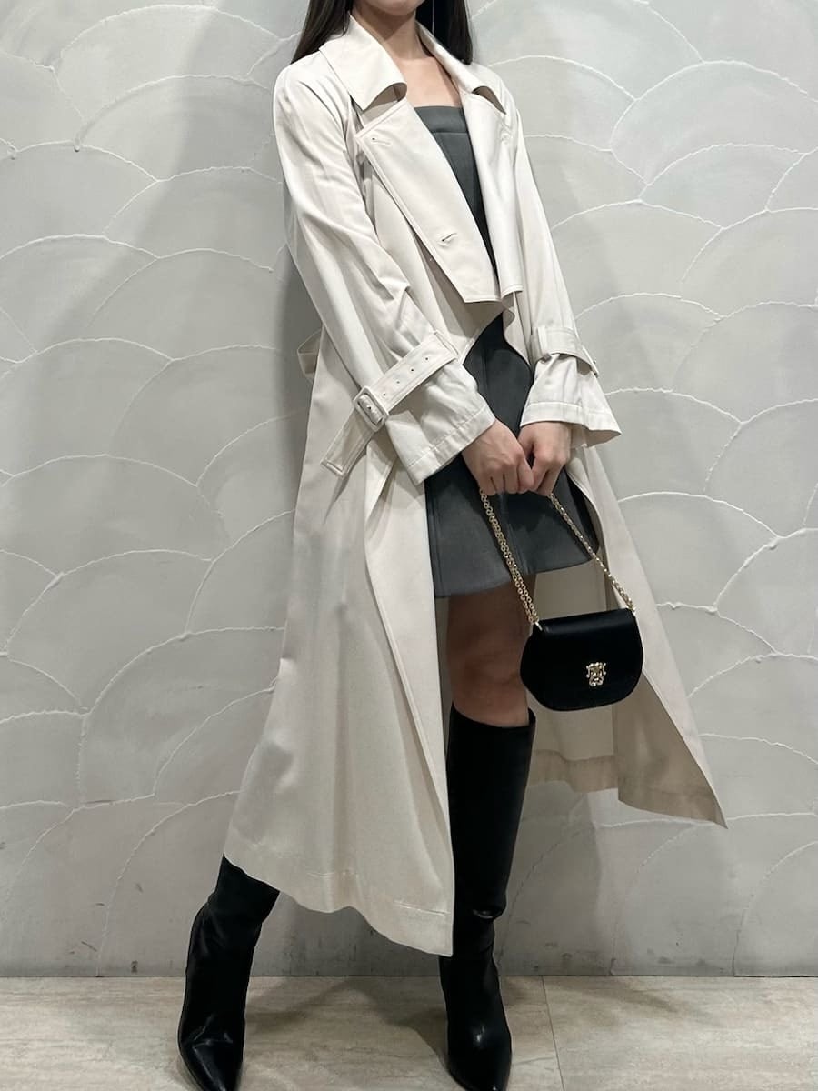 ブラック系のブーツ、ホワイト系のトレンチコート、グレー系のワンピースを着用したレディースの冬コーディネートの2枚目の写真