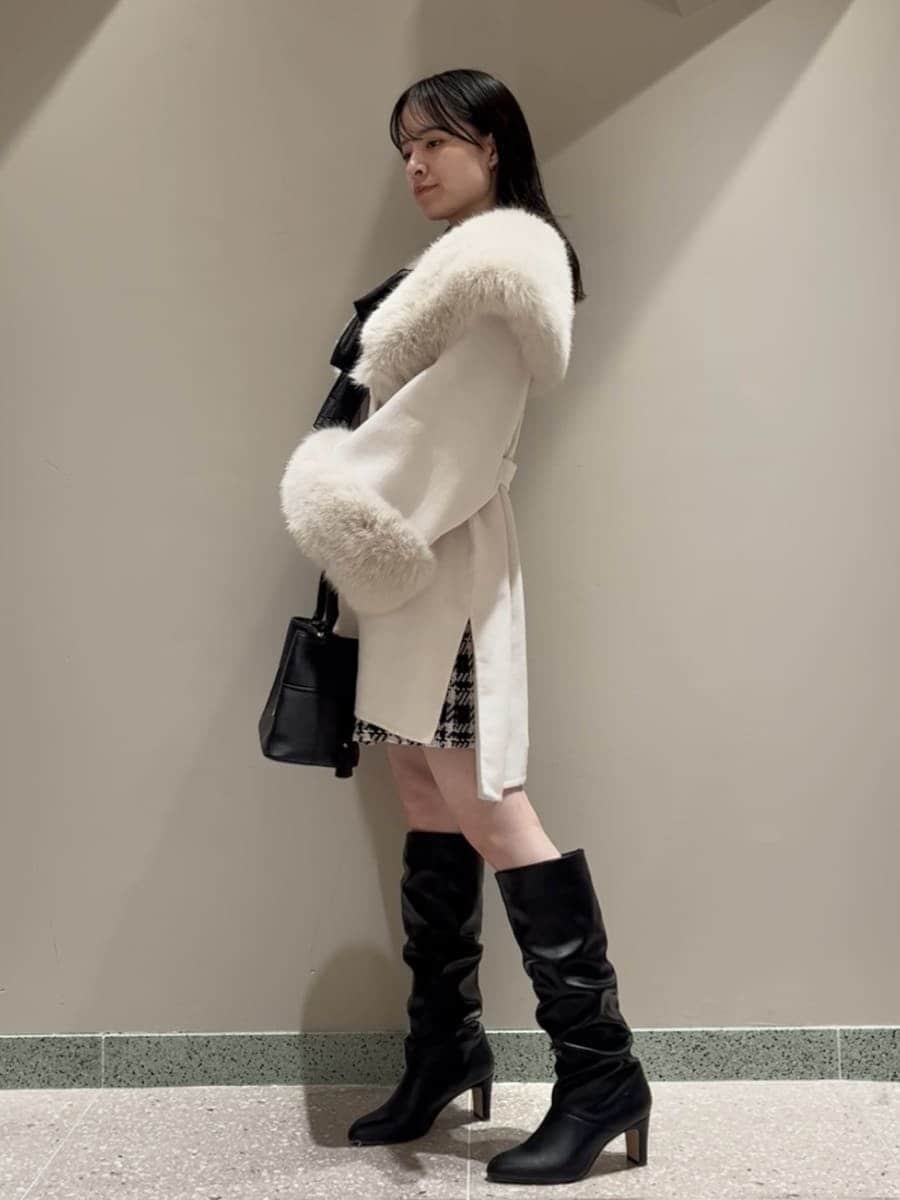 ホワイト系のチェスターコート、ブラック系のその他パンツ、ブラック系のハンドバッグを着用したレディースの冬コーディネートの2枚目の写真