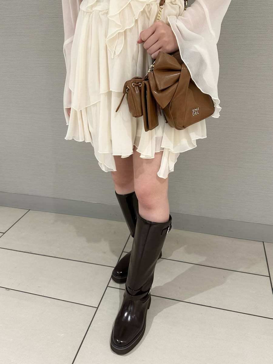 ブラウン系のブーツ、ホワイト系のワンピース、イエロー系のショルダーバッグを着用したレディースの冬コーディネートの5枚目の写真