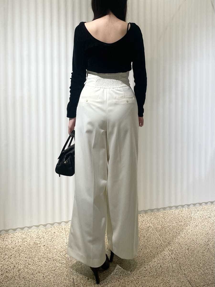 ベージュ系のチェスターコート、ブラック系のTシャツ/カットソー、ホワイト系のスラックスを着用したレディースの秋コーディネートの4枚目の写真