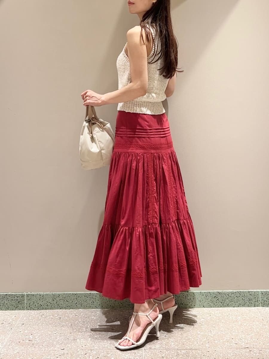 ホワイト系のニット/セーター、レッド系のスカート、ベージュ系のハンドバッグを着用したレディースの夏コーディネートの2枚目の写真