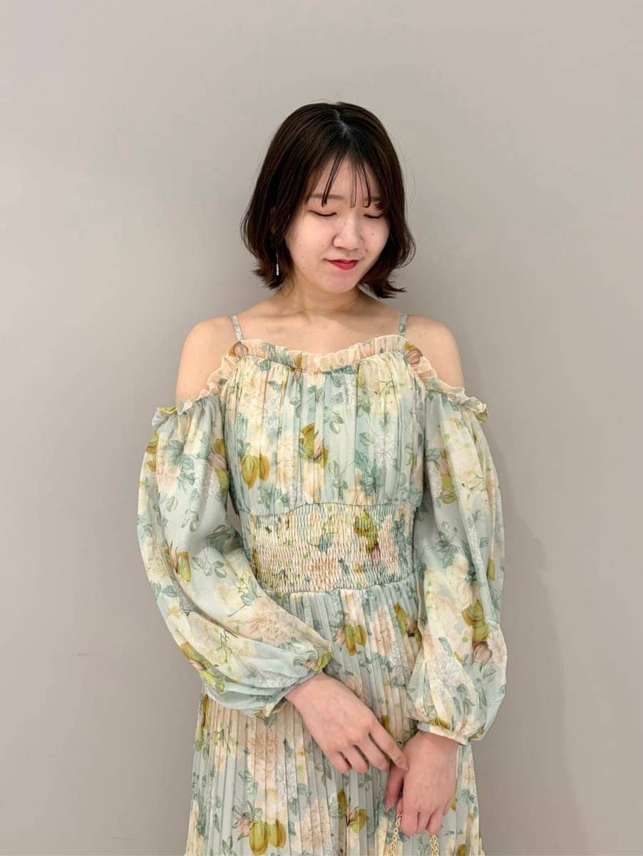 グリーン系のワンピース、ブラック系のショルダーバッグ、その他のイヤリングを着用したレディースの春コーディネートの2枚目の写真