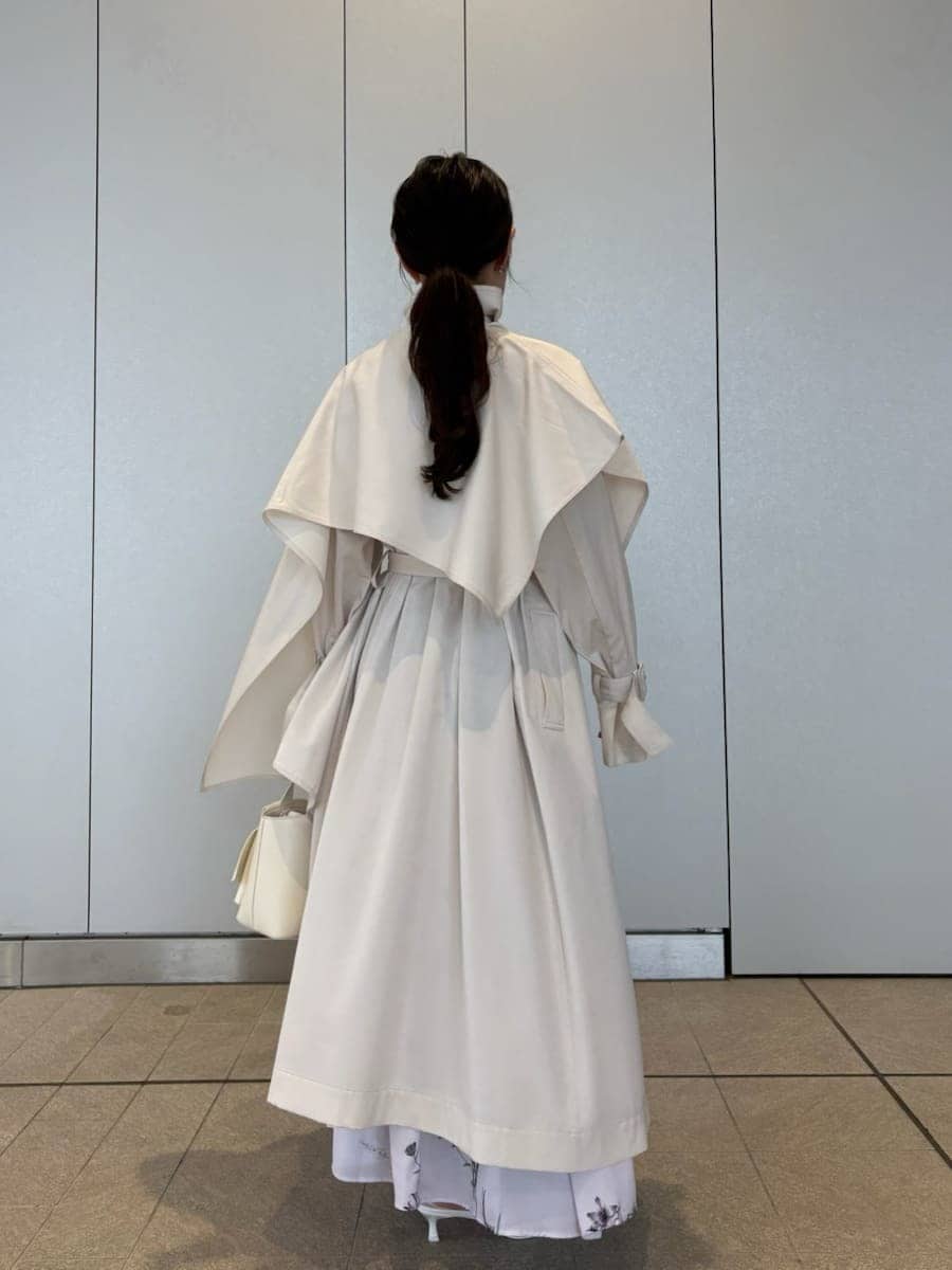 ホワイト系のトレンチコート、パープル系のワンピース、その他のパンプスを着用したレディースの冬コーディネートの10枚目の写真