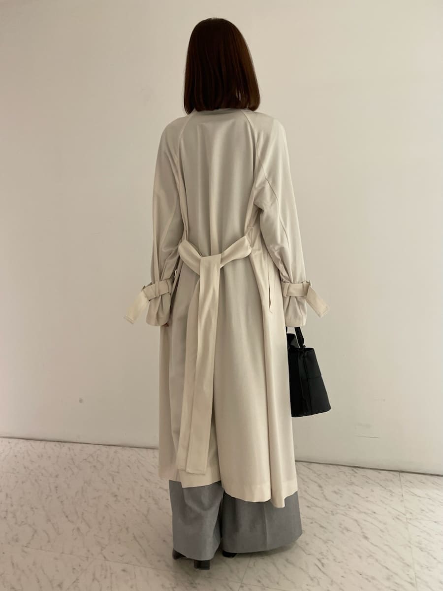 ブラック系のショルダーバッグ、ブラック系のニット/セーター、ホワイト系のトレンチコートを着用したレディースの冬コーディネートの3枚目の写真