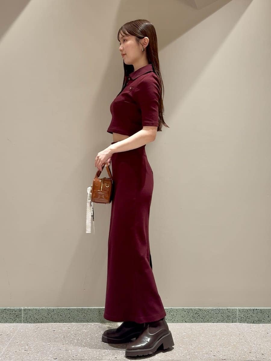 ブラウン系のワンピース、ブラウン系のボストンバッグ、ホワイト系のチャームを着用したレディースの秋コーディネートの2枚目の写真