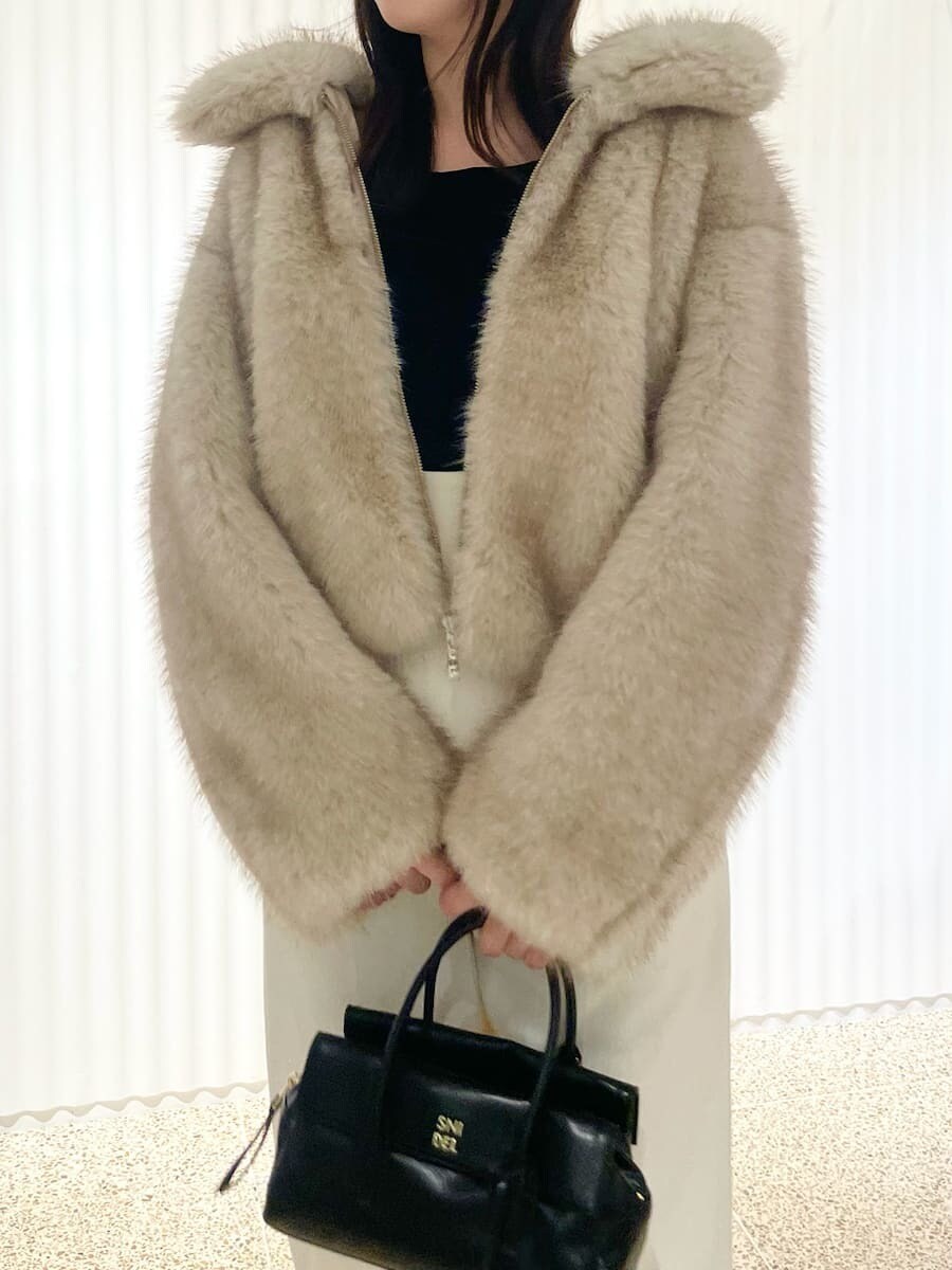 ベージュ系のチェスターコート、ブラック系のTシャツ/カットソー、ホワイト系のスラックスを着用したレディースの秋コーディネートの5枚目の写真