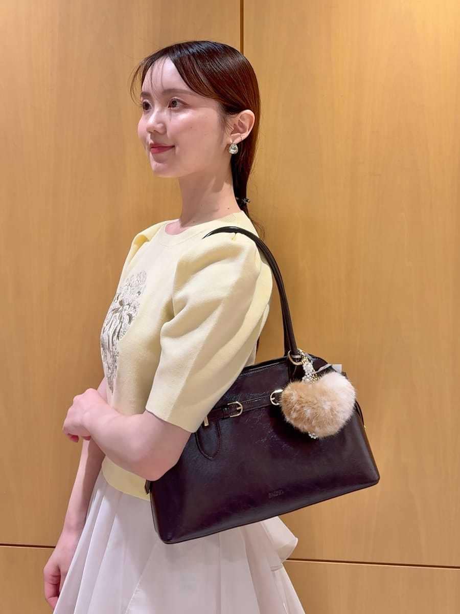 ホワイト系のスカート、イエロー系のニット/セーター、ブラウン系のボストンバッグを着用したレディースの夏コーディネートの4枚目の写真