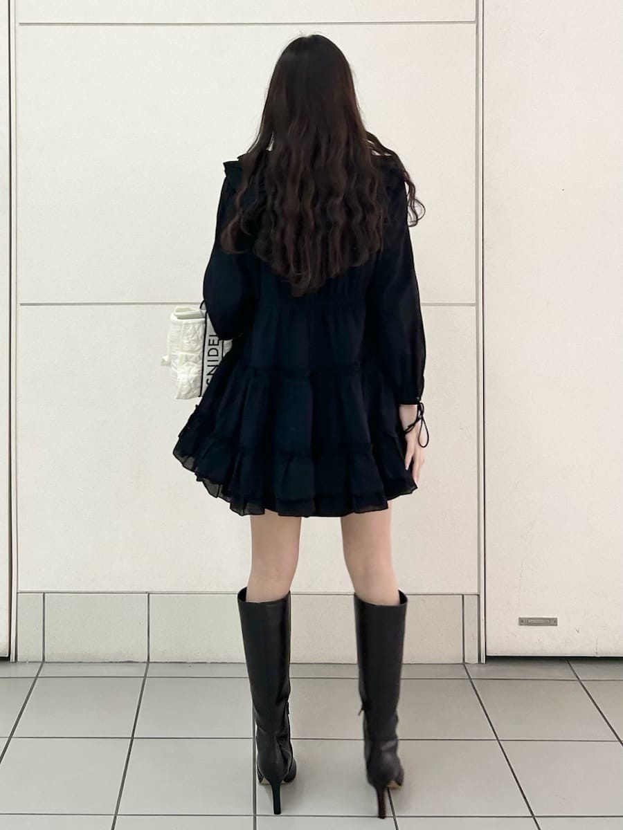 ブラック系のブーツ、ホワイト系のハンドバッグ、ブラック系のスカートを着用したレディースの冬コーディネートの4枚目の写真