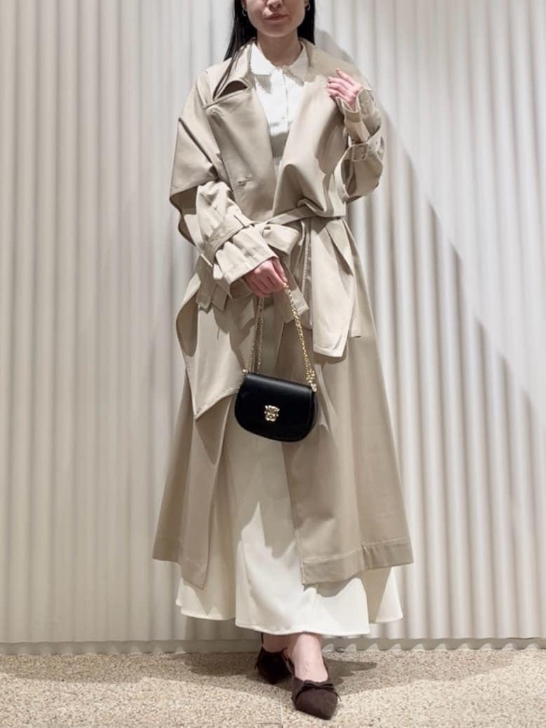 ベージュ系のトレンチコート、ホワイト系のスカート、ブラウン系のパンプスを着用したレディースの冬コーディネートの4枚目の写真