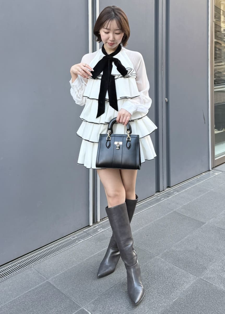 ホワイト系のドレス、ブラック系のハンドバッグを着用したレディースの冬コーディネートの2枚目の写真