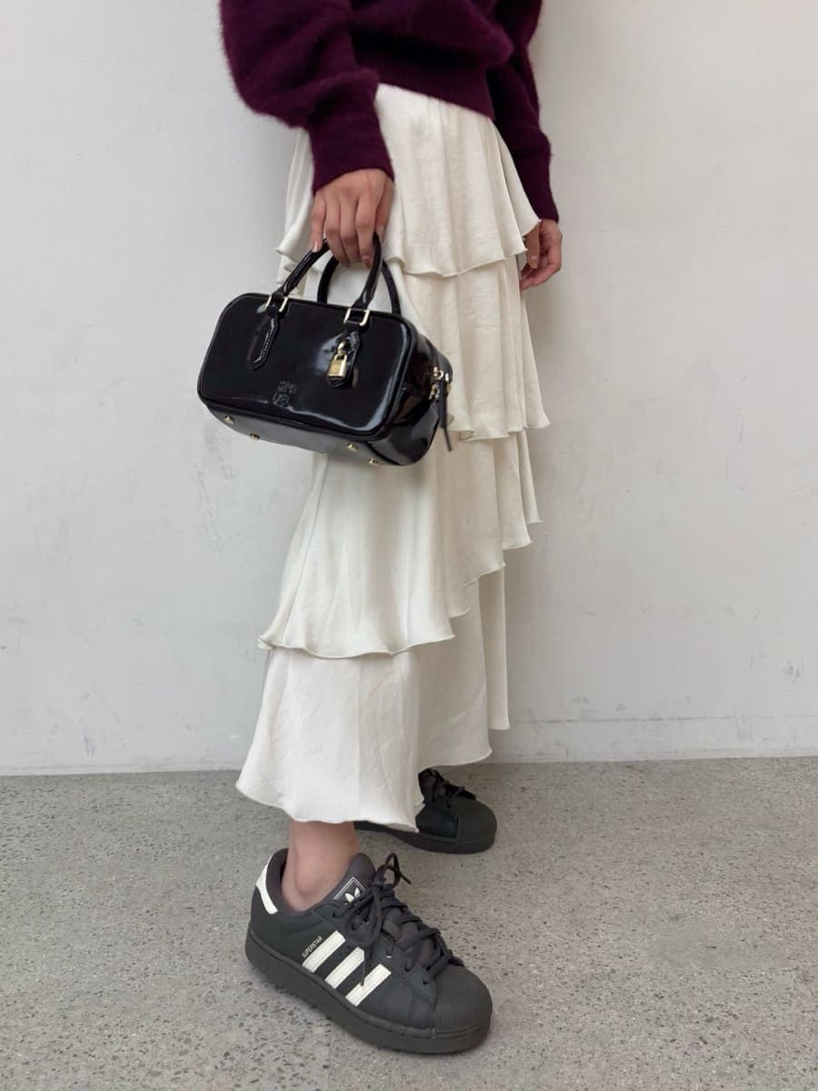 レッド系のニット/セーター、ホワイト系のスカート、グレー系のスニーカーを着用したレディースの秋コーディネートの7枚目の写真