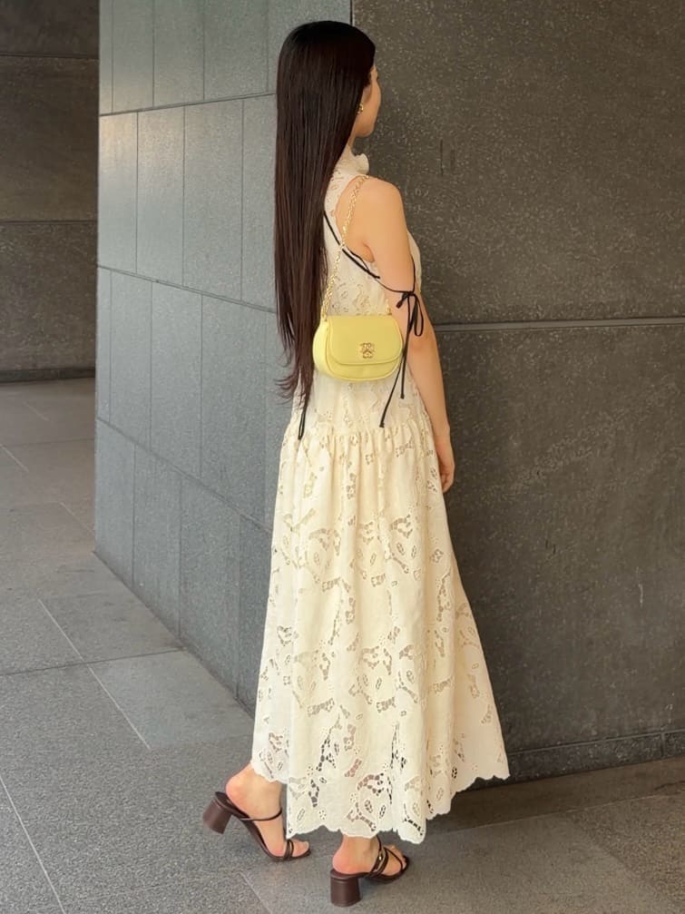 イエロー系のショルダーバッグ、ホワイト系のワンピース、ブラウン系のサンダルを着用したレディースの夏コーディネートの4枚目の写真