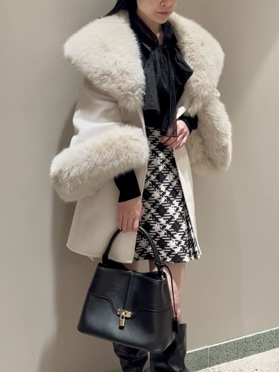 ホワイト系のチェスターコート、ブラック系のその他パンツ、ブラック系のハンドバッグを着用したレディースの冬コーディネートの5枚目の写真