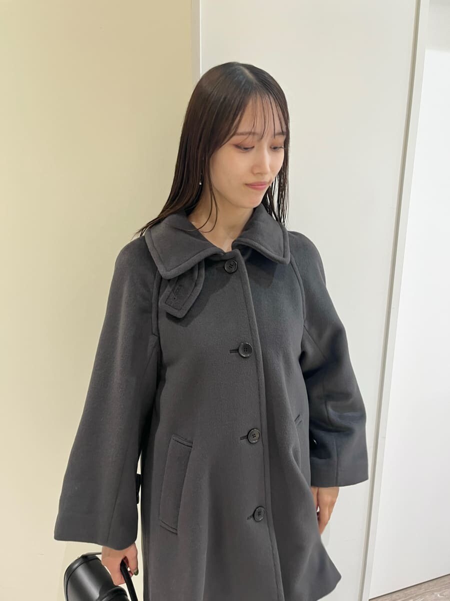 グレー系のステンカラーコート、レッド系のニット/セーター、ブルー系のデニムパンツを着用したレディースの秋コーディネートの5枚目の写真