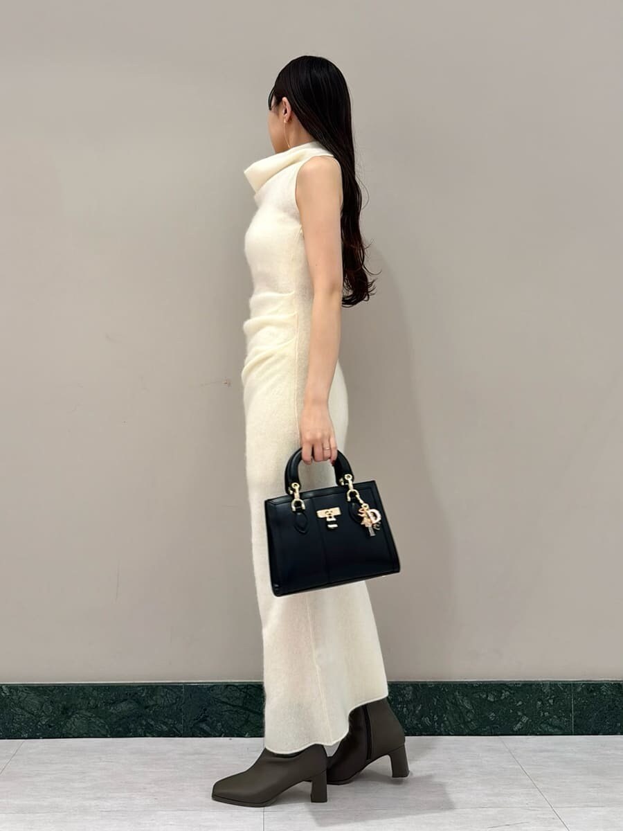 ホワイト系のワンピース、ブラック系のハンドバッグ、ブラウン系のチェスターコートを着用したレディースの冬コーディネートの6枚目の写真