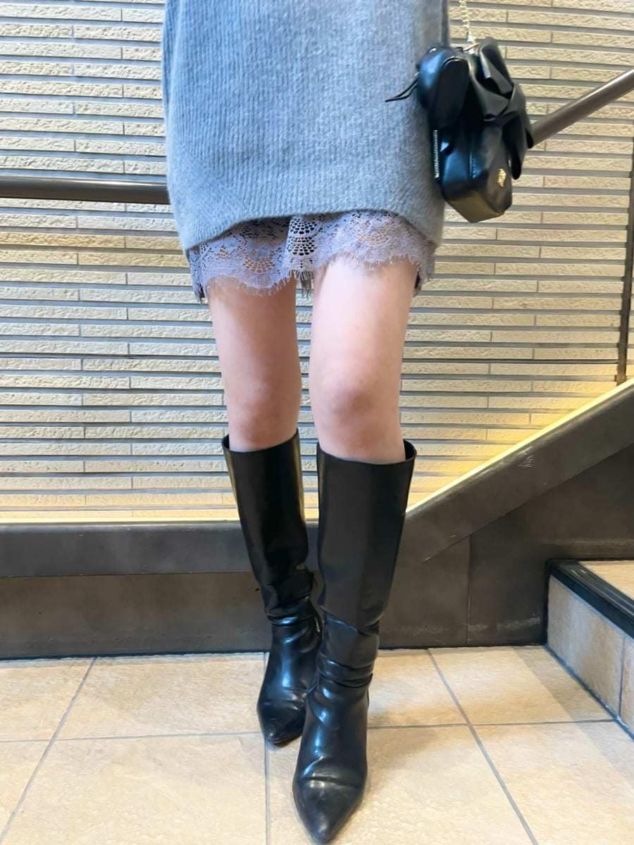 グレー系のワンピース、ブラック系のブーツ、ホワイト系のチェスターコートを着用したレディースの冬コーディネートの7枚目の写真