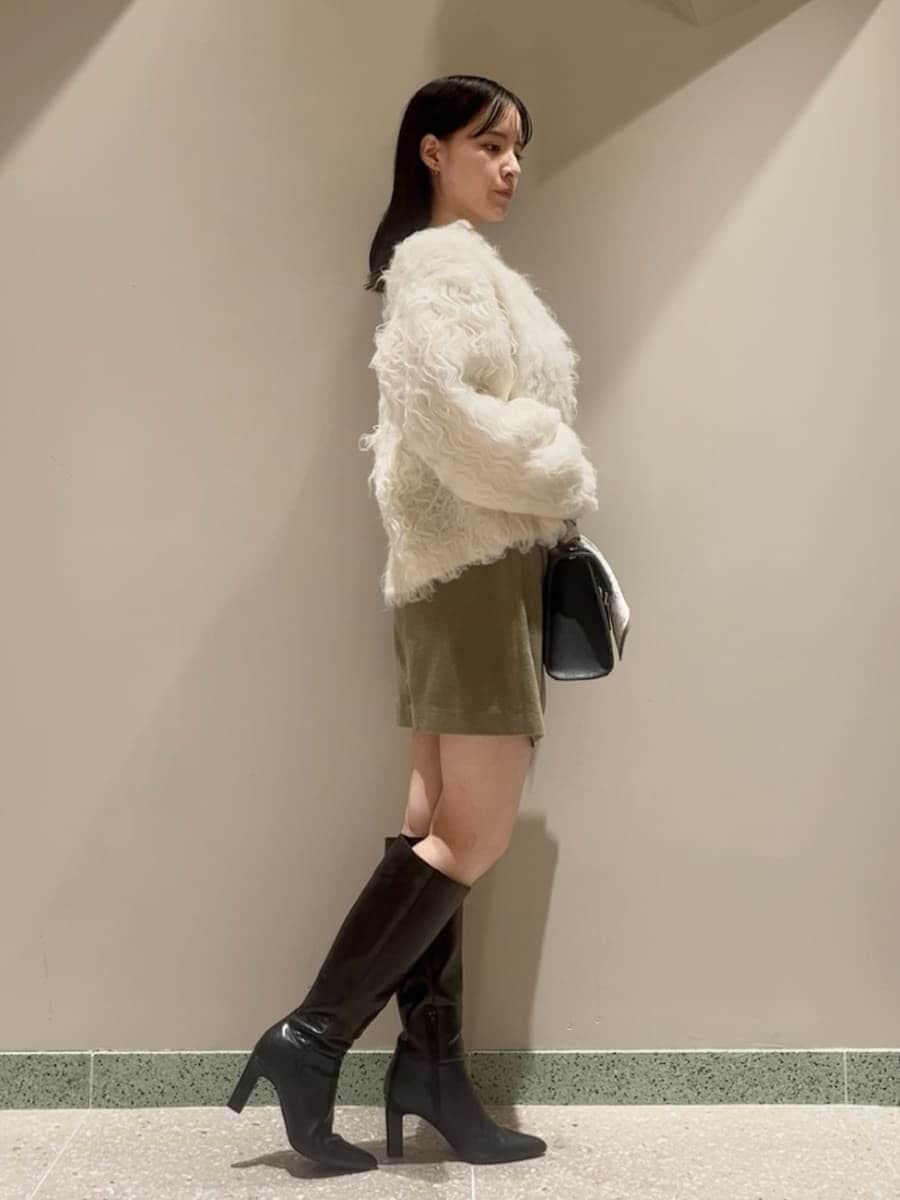 グリーン系のワンピース、ホワイト系のカーディガン/ボレロ、ブラック系のブーツを着用したレディースの秋コーディネートの2枚目の写真