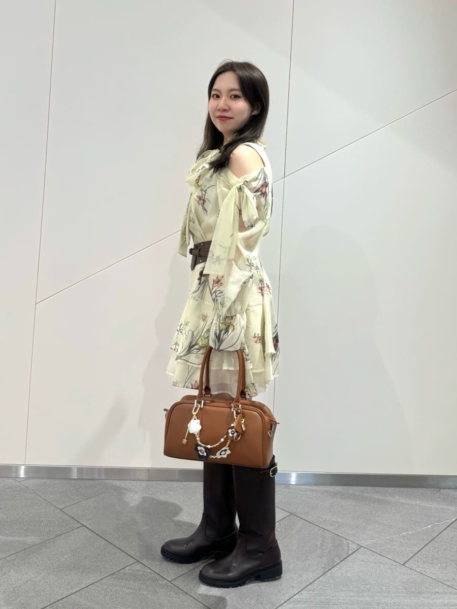 ブルー系のワンピース、イエロー系のボストンバッグ、ブラウン系のベルトを着用したレディースの冬コーディネートの3枚目の写真