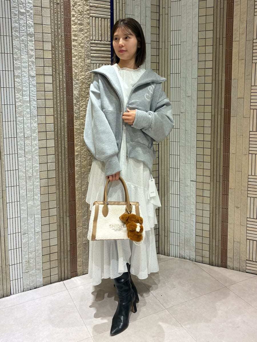 イエロー系のトートバッグ、ブラック系のブーツ、その他のワンピースを着用したレディースの冬コーディネートの4枚目の写真