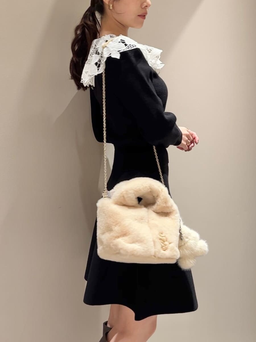 ホワイト系のステンカラーコート、イエロー系のハンドバッグ、ブラック系のワンピースを着用したレディースの冬コーディネートの9枚目の写真